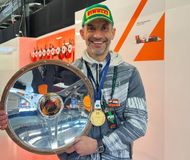 Formula 1 driver Lando Norris' father, Adam Norris, wears his medal and podium cap as he holds Lando's Australian Grand Prix trophy. (Image via X/@ln4norris)